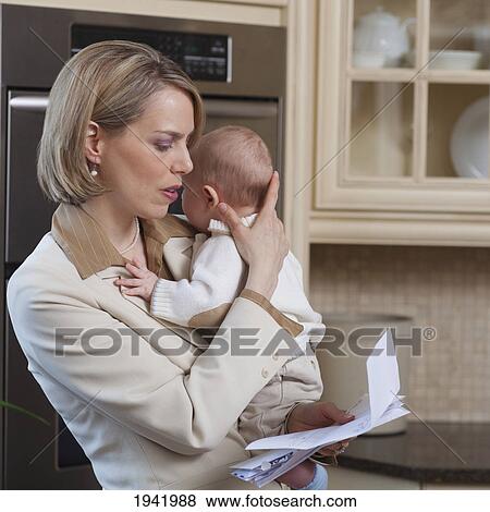 Stock Photo - Mother With Baby Stressing Over Household Bills; Jordan Ontario Canada. Fotosearch