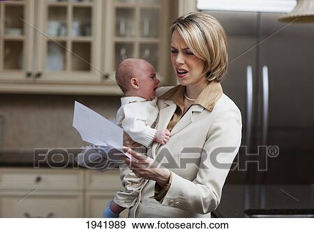 Stock Photo - Mother With Baby Stressing Over Household Bills; Jordan Ontario Canada. Fotosearch