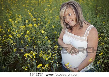 Portrait Of A Pregnant Young Woman Holding Her Belly In A Field Of Yellow Wildflowers; Edmonton Alberta Canada View Large Photo Image Stock Image - Portrait Of A Pregnant Young Woman Holding Her Belly In A Field Of Yellow Wildflowers; Edmonton Alberta Canada. Fotosearch
