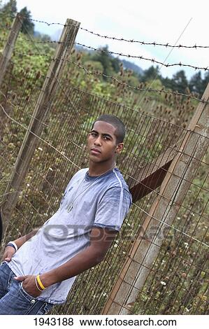 Portrait Of A Teenage Boy Leaning Against A Fence; Troutdale Oregon United States Of America View Large Photo Image Stock Photo - Portrait Of A Teenage Boy Leaning Against A Fence; Troutdale Oregon United States Of America. Fotosearch
