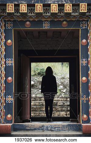 Stock Photograph - Silhouette Of A Woman Standing In A Doorway Of A Temple; Tamchhog Lhakhang Bhutan. Fotosearch