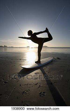 Stock Image - Silhouette Of Female Surfer Doing Bow Pulling Yoga Pose; Chesterman Beach Tofino Vancouver Island British Columbia Canada. Fotosearch