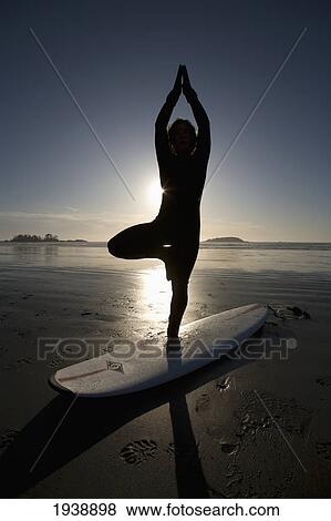 Stock Photo - Silhouette Of Female Surfer Doing Yoga Tree Pose; Chesterman Beach Tofino Vancouver Island British Columbia Canada. Fotosearch