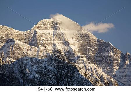 Snow-Capped Mountain Peak At Sunset; Waterton Alberta Canada View Large Photo Image Stock Photo - Snow-Capped Mountain Peak At Sunset; Waterton Alberta Canada. Fotosearch