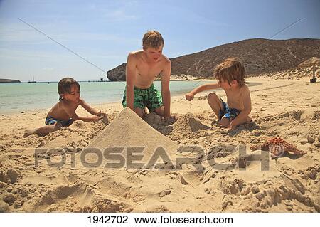 Stock Image - Three Boys Play In The Sand At The Water's Edge At Los Islotes National Marine Park Espiritu Santo Island; La Paz Baja California Mexico. Fotosearch