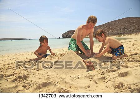 Stock Image - Three Boys Play In The Sand At The Water's Edge At Los Islotes National Marine Park Espiritu Santo Island; La Paz Baja California Mexico. Fotosearch