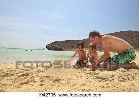Stock Photography - Three Boys Play In The Sand At The Water's Edge At Los Islotes National Marine Park Espiritu Santo Island; La Paz Baja California Mexico. Fotosearch