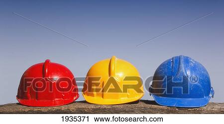 Stock Image - Three Hard Hats In A Row In Primary Colors Red, Yellow And Blue. Fotosearch
