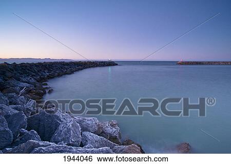 Stock Photograph - Tranquil Scene Of Blue Water Along The Coast At Sunset; New Zealand. Fotosearch