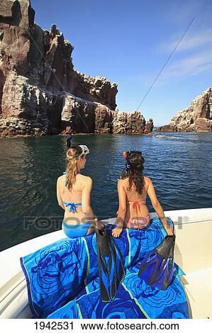 Stock Image - Two Females With Snorkeling Gear Sit On The Edge Of A Boat At Los Islotes National Marine Park Espiritu Santo Island; La Paz Baja California Mexico. Fotosearch