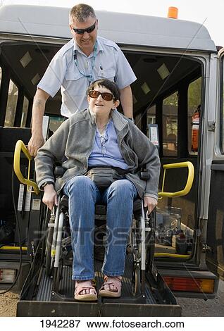 Stock Photo - Two Friends Getting Off The Bus With A Wheelchair; Bolton Lancashire England. Fotosearch