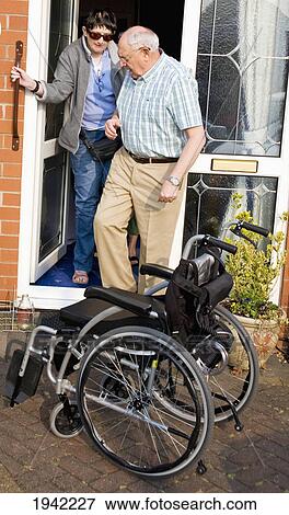 Two Friends Helping Each Other Get Out Of The Door To Wheelchair; Bolton Lancashire England View Large Photo Image Stock Photo - Two Friends Helping Each Other Get Out Of The Door To Wheelchair; Bolton Lancashire England. Fotosearch