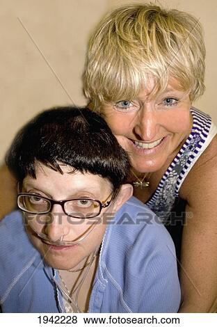Stock Photo - Two Friends Sharing A Hug One Woman With An Oxygen Supply Hose; Bolton Lancashire England. Fotosearch