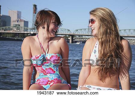 Two Teenage Girls In Bathing Suits On The Back Of A Boat Laughing With A Bridge And City In The Background; Portland Oregon United States Of America View Large Photo Image Stock Photo - Two Teenage Girls In Bathing Suits On The Back Of A Boat Laughing With A Bridge And City In The Background; Portland Oregon United States Of America. Fotosearch