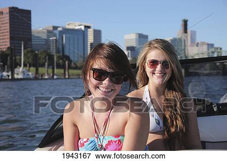 Two Teenage Girls In Bathing Suits Sitting In The Back Of A Boat With The City In The Background; Portland Oregon United States Of America View Large Photo Image Stock Photo - Two Teenage Girls In Bathing Suits Sitting In The Back Of A Boat With The City In The Background; Portland Oregon United States Of America. Fotosearch