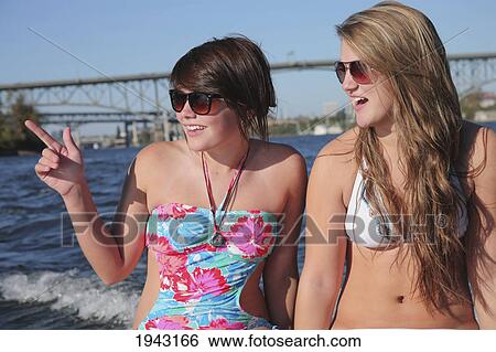 Stock Photograph - Two Teenage Girls In Bathing Suits Sitting On The Back Of A Boat; Portland Oregon United States Of America. Fotosearch