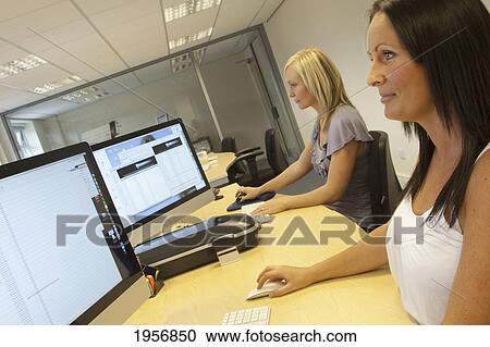 two young women sitting in front of their computer monitors at work; south shields tyne and wear england View Large Photo Image Stock Image - two young women sitting in front of their computer monitors at work; south shields tyne and wear england. Fotosearch