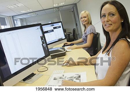 two young women sitting in front of their computer monitors at work; south shields tyne and wear england View Large Photo Image Stock Photo - two young women sitting in front of their computer monitors at work; south shields tyne and wear england. Fotosearch