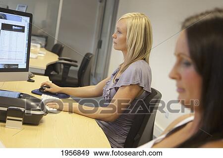 two young women sitting in front of their computer monitors at work; south shields tyne and wear england View Large Photo Image Stock Photo - two young women sitting in front of their computer monitors at work; south shields tyne and wear england. Fotosearch