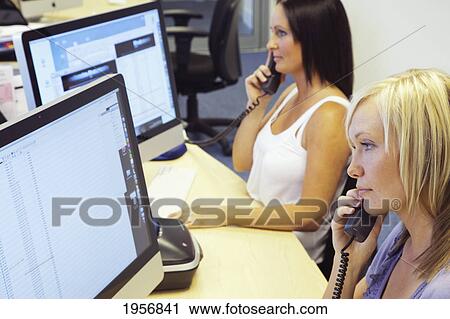 two young women talking on the phone and sitting in front of their computer screens at work; south shields tyne and wear england View Large Photo Image Stock Image - two young women talking on the phone and sitting in front of their computer screens at work; south shields tyne and wear england. Fotosearch