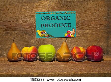 Stock Image - variety of fruit in a row on a wooden shelf with an organic produce sign; waterloo quebec canada. Fotosearch