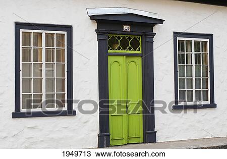 Stock Image - windows on either side of a green door; trois riviere quebec canada. Fotosearch