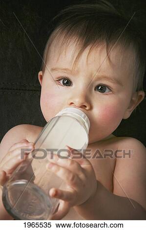 Stock Photography - a baby laying on it's back drinking milk from a bottle; edmonton alberta canada. Fotosearch