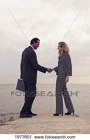 a businessman and businesswoman shake hands while standing on a dock at the water's edge; tarifa cadiz andalusia spain View Large Photo Image Stock Image - a businessman and businesswoman shake hands while standing on a dock at the water's edge; tarifa cadiz andalusia spain. Fotosearch