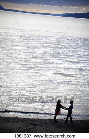 Stock Photo - a couple on the beach on the water's edge; bellingham washington united states of america. Fotosearch