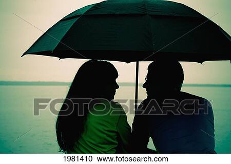 a couple sits under an umbrella at the water's edge; bellingham washington united states of america View Large Photo Image Stock Image - a couple sits under an umbrella at the water's edge; bellingham washington united states of america. Fotosearch
