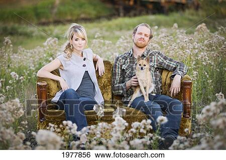 a couple sitting on a couch with their dog in a field of wildflowers; edmonton alberta canada View Large Photo Image Stock Photograph - a couple sitting on a couch with their dog in a field of wildflowers; edmonton alberta canada. Fotosearch