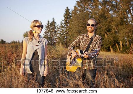 a couple standing in a field with a guitar; edmonton alberta canada View Large Photo Image Stock Photo - a couple standing in a field with a guitar; edmonton alberta canada. Fotosearch