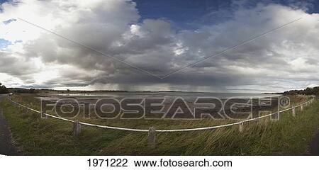 Stock Image - a curved fence along the water's edge at budle bay; northumberland england. Fotosearch