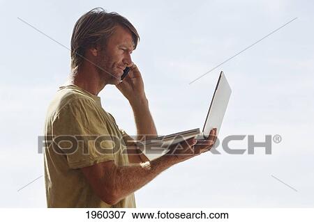 a man reading from his portable computer screen while talking on the phone; torremolinos, malaga province, spain View Large Photo Image Stock Photo - a man reading from his portable computer screen while talking on the phone; torremolinos, malaga province, spain. Fotosearch