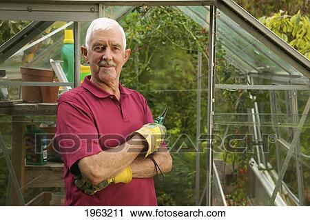 a man standing outside a greenhouse wearing gardening gloves; naas, county kildare, ireland View Large Photo Image Stock Image - a man standing outside a greenhouse wearing gardening gloves; naas, county kildare, ireland. Fotosearch