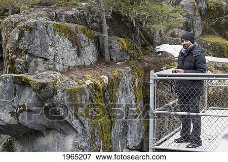 a man stands on a fenced lookout point by moss covered rock in jasper national park; alberta canada View Large Photo Image Stock Photo - a man stands on a fenced lookout point by moss covered rock in jasper national park; alberta canada. Fotosearch