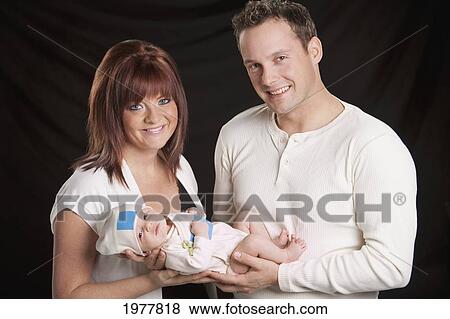 Stock Photo - a mother and father hold a newborn baby; edmonton alberta canada. Fotosearch
