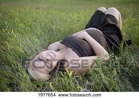 a pregnant woman lays on her back in the grass; edmonton alberta canada View Large Photo Image Picture - a pregnant woman lays on her back in the grass; edmonton alberta canada. Fotosearch