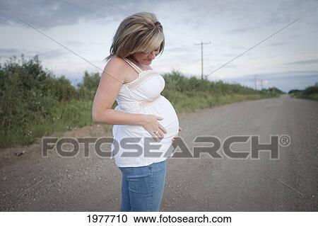 a pregnant woman stands on a dirt road; edmonton alberta canada View Large Photo Image Stock Image - a pregnant woman stands on a dirt road; edmonton alberta canada. Fotosearch