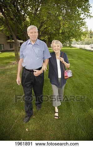 a senior couple walks together across the grass; edmonton, alberta, canada View Large Photo Image Stock Image - a senior couple walks together across the grass; edmonton, alberta, canada. Fotosearch