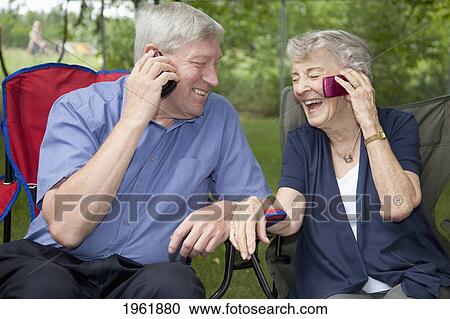 a senior man and woman sitting side by side and each talking on a cell phone; edmonton, alberta, canada View Large Photo Image Stock Image - a senior man and woman sitting side by side and each talking on a cell phone; edmonton, alberta, canada. Fotosearch