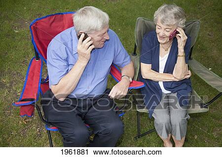 a senior man and woman sitting side by side and each talking on a cell phone; edmonton, alberta, canada View Large Photo Image Stock Image - a senior man and woman sitting side by side and each talking on a cell phone; edmonton, alberta, canada. Fotosearch