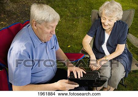 Picture - a senior man and woman sitting together using a laptop computer; edmonton, alberta, canada. Fotosearch