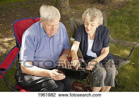 a senior man and woman sitting together using a laptop computer; edmonton, alberta, canada View Large Photo Image Stock Image - a senior man and woman sitting together using a laptop computer; edmonton, alberta, canada. Fotosearch