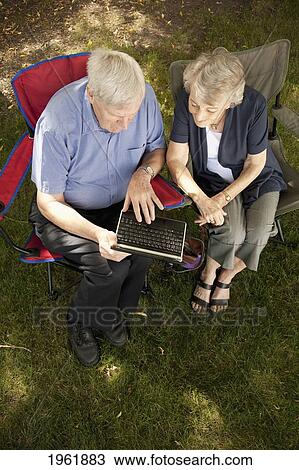 a senior man and woman sitting together using a laptop computer; edmonton, alberta, canada View Large Photo Image Stock Image - a senior man and woman sitting together using a laptop computer; edmonton, alberta, canada. Fotosearch