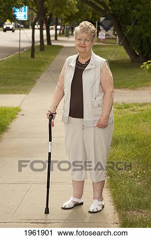 a senior woman standing with her cane on the sidewalk; edmonton, alberta, canada View Large Photo Image Stock Image - a senior woman standing with her cane on the sidewalk; edmonton, alberta, canada. Fotosearch