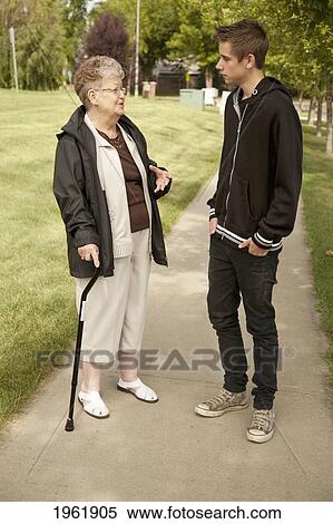 Stock Photography - a senior woman talking with a teenage boy; edmonton, alberta, canada. Fotosearch