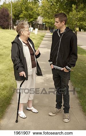 Stock Photo - a senior woman talks with a teenage boy; edmonton, alberta, canada. Fotosearch