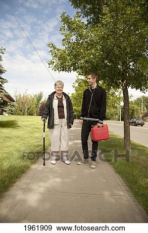 Stock Photo - a senior woman walks and talks with a teenage boy; edmonton, alberta, canada. Fotosearch