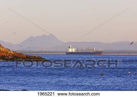Stock Image - a ship travels by cape disappointment at sunset; ilwaco washington united states of america. Fotosearch